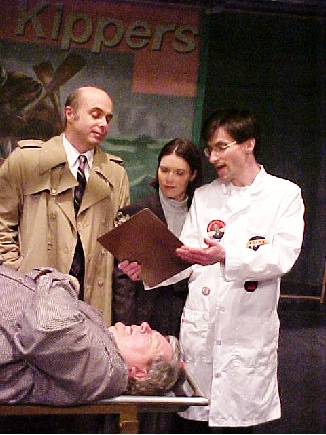The coroner (David DelBianco) reviews his report on a mysterious corpse (Jim Mason) for officers Frank Keller (Jim Ludovici) and Maggie Pelletier (Vania Falen)